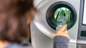 Woman at the reverse vending machine recycle plastic bottles, ecology concept